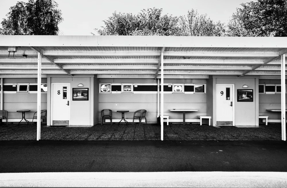 Svartvit bild med enplans motellrum.