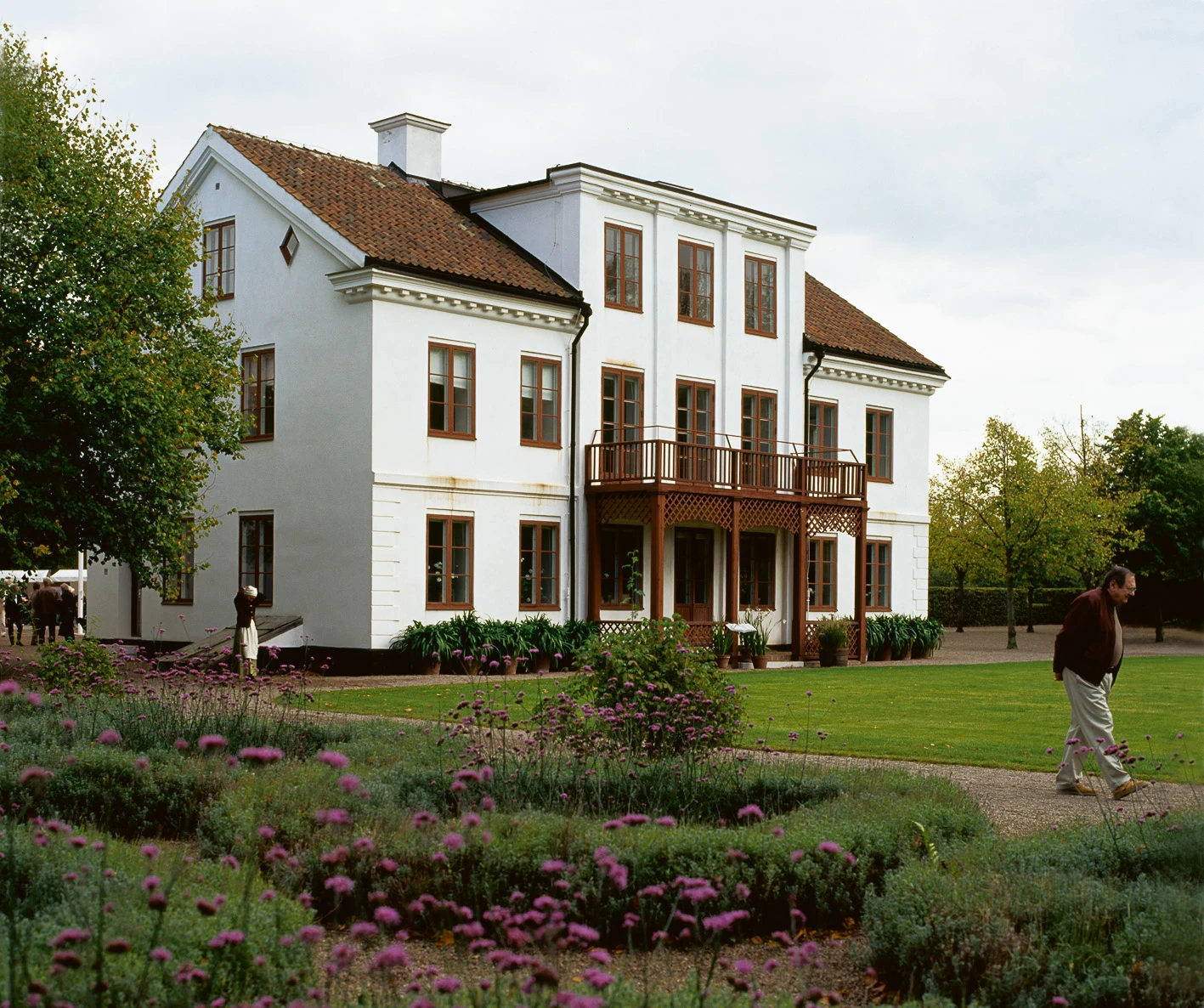 Vitmenad tvåvåningsbyggnad med rösa detaljer.