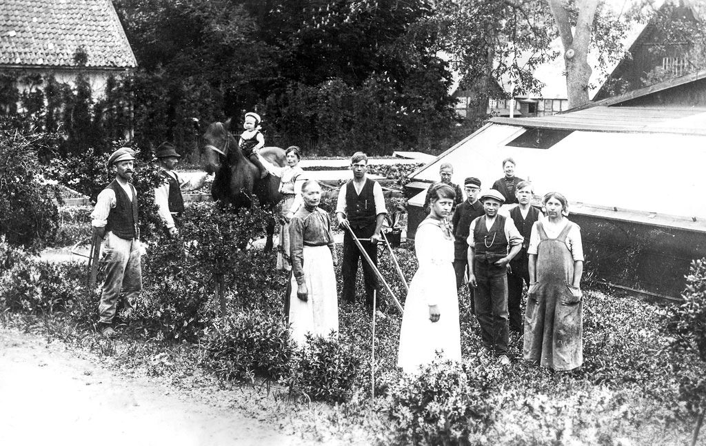 Fotot, som är taget år 1918, visar platsen där växthusen var belägna. I bakgrunden till vänster på bilden skymtar södra flygeln, där trädgårdsmästaren bodde. Från vänster ser vi trädgårdsmästare J.P. Svensson med familj. Mannen med skyffelmaskin i mitten på bilden är Knut Svensson. Övriga personer är anställda och trädgårdselever på trädgårdsmästeriet.Foto ur Björn Engdahls samlingar.