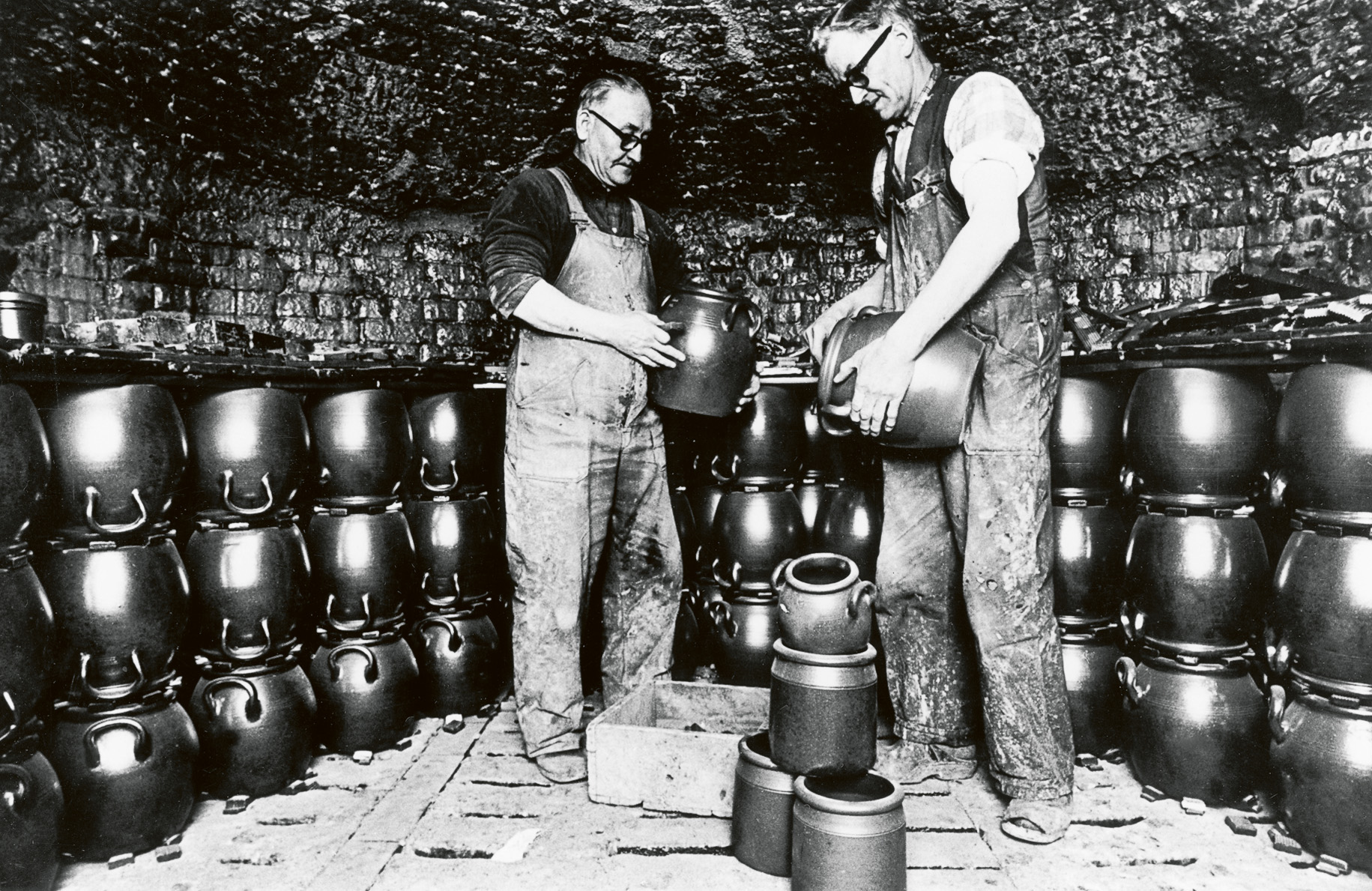 Raus stenkärlsfabrik, och de legendariska krukmakarna Olof Nilsson och Hugo Anderberg slår bort lerbrickor i ugnen. Foto omkring 1970
