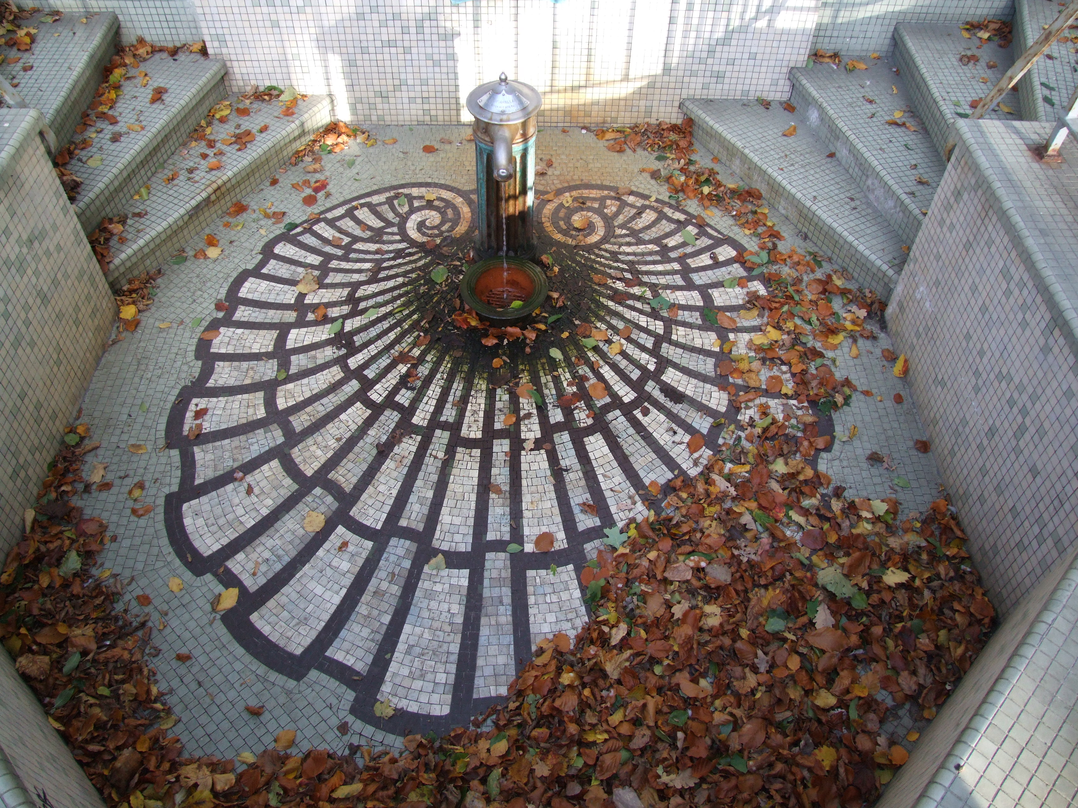 Mosaik i form av snäcka vid en vattenpost. 