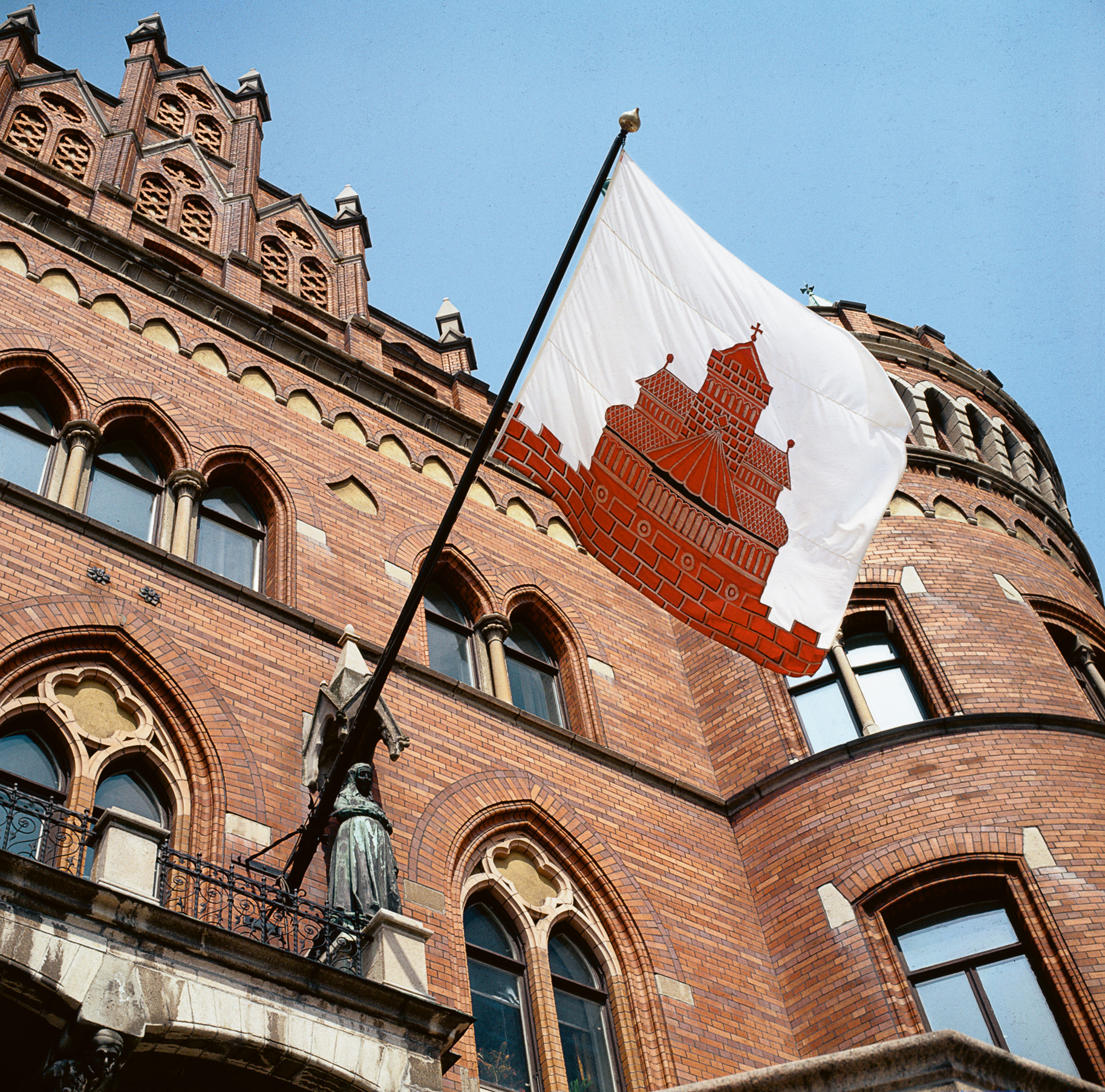 Stadsflaggan med stadens vapen på rådhusets fasad