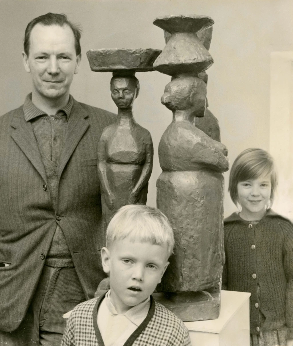 Man med en skulptur och två små barn.