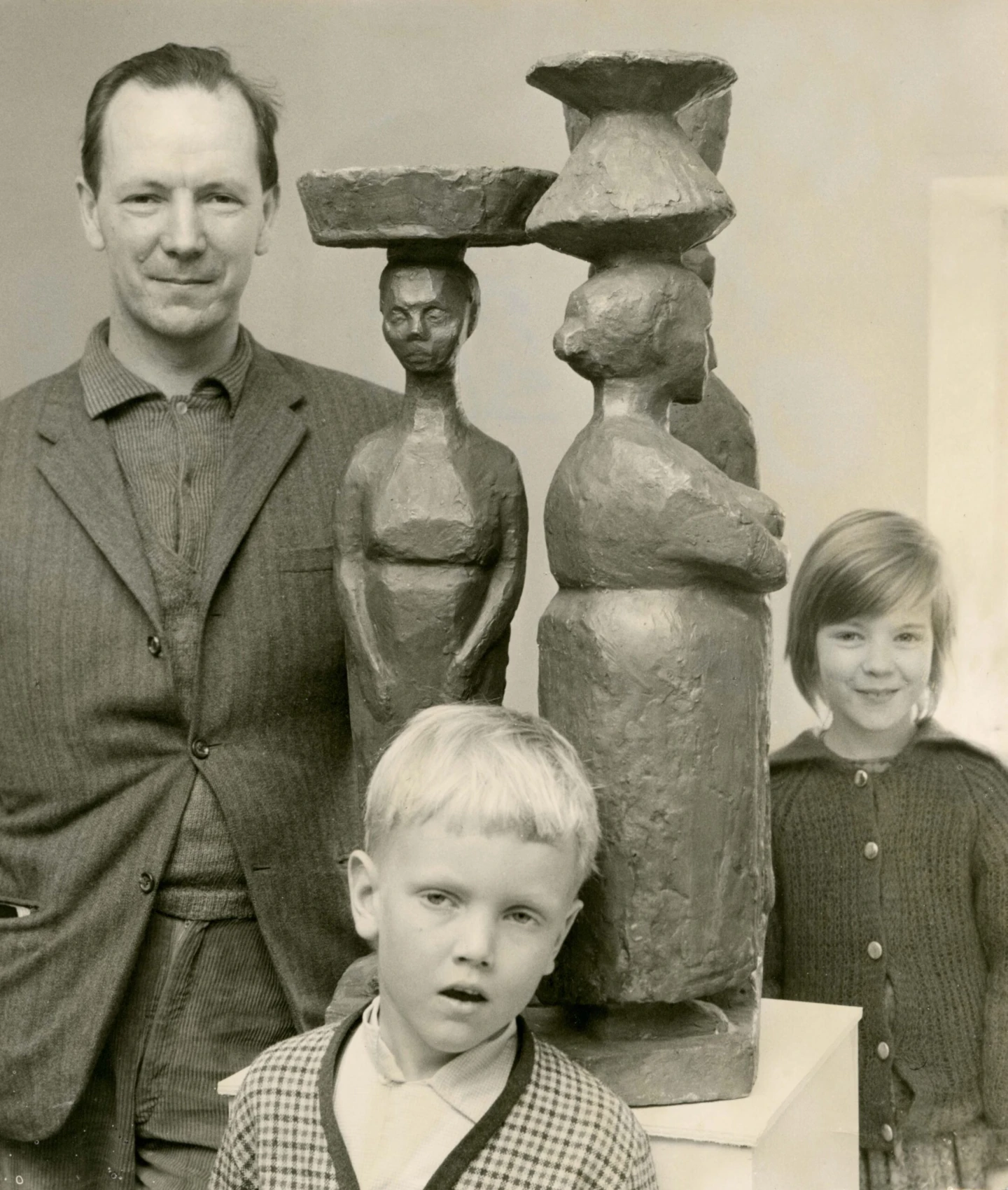 Man med en skulptur och två små barn.