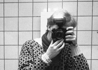 Fotograf Per Drejare tar en bild på sig själv i en spegel med kakel bakom sig.