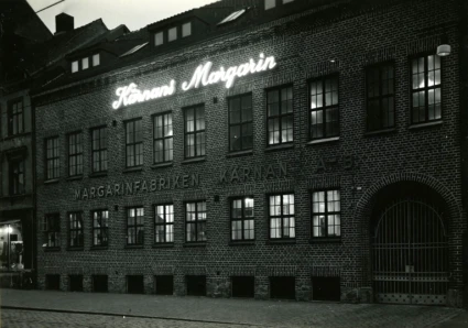 Margarinfabriken Kärnan ABs upplysta fasad kvällstid. Adress: Södergatan 82. Fotograf: Tönnessen. Fotot tillhör Jan Sendelius.