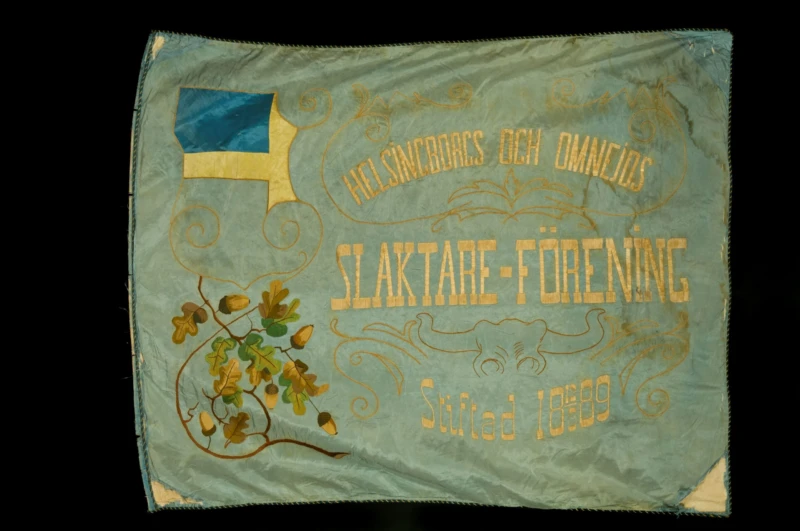 Fanans baksida med texten: "Helsingborgs och omnejds slaktareförening stiftad 12/3 1889".