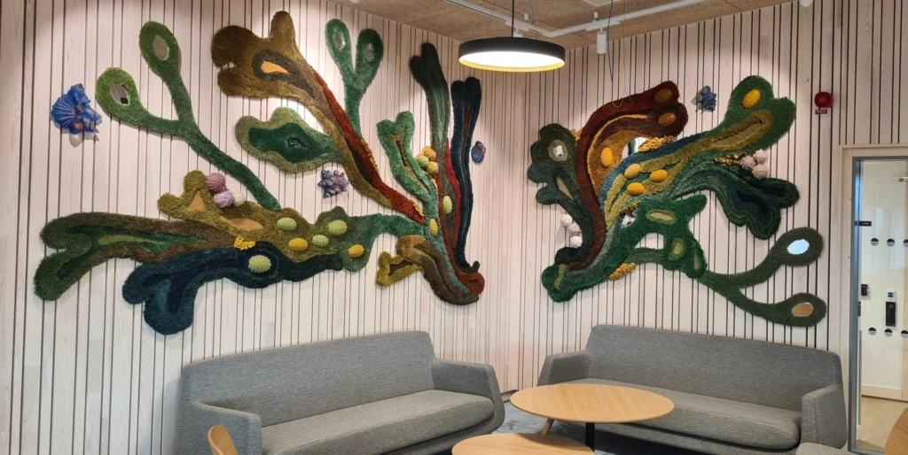 Hörna med soffa, textilverk liknande mörk tång på väggen.