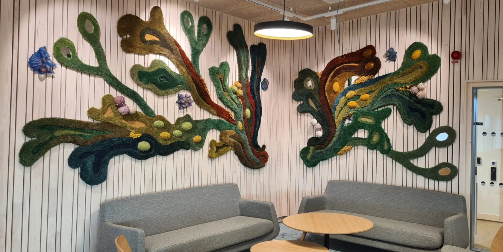 Hörna med soffa, textilverk liknande mörk tång på väggen.