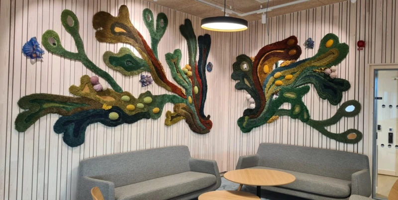 Hörna med soffa, textilverk liknande mörk tång på väggen.