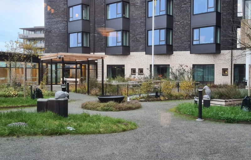 Innergård med planteringar och skulpturer, en kungsfiskare och en snäcka.