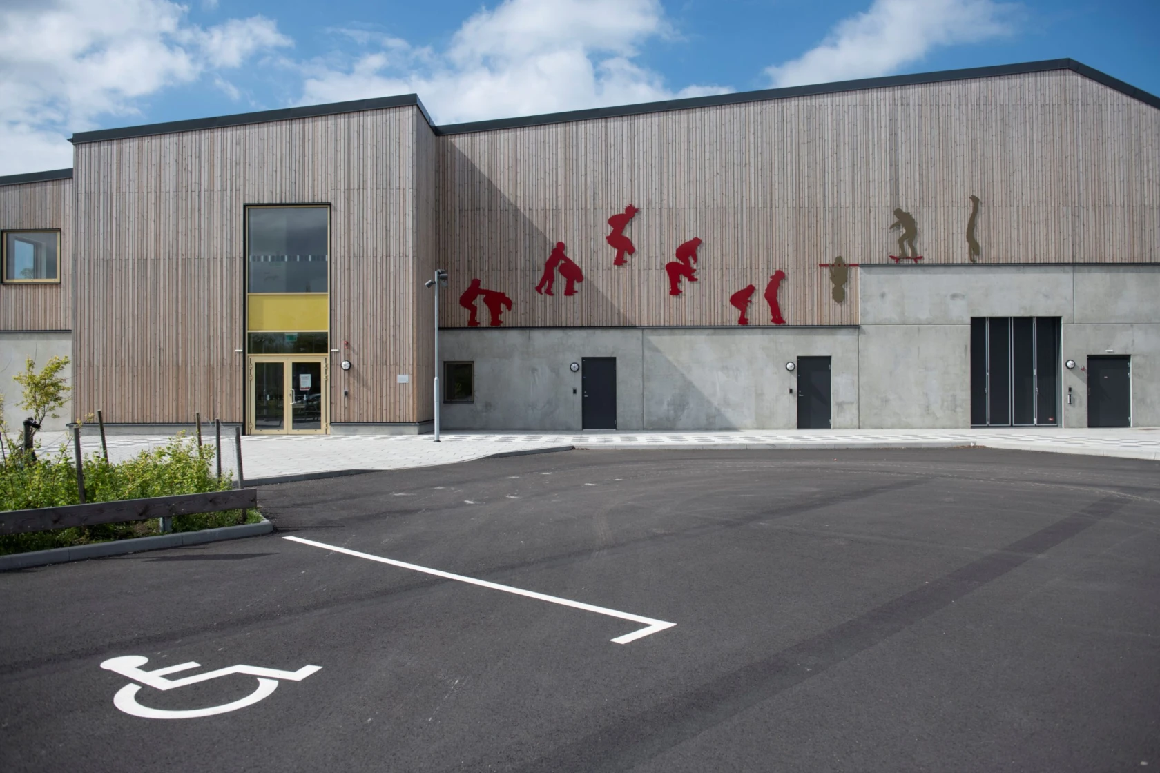 Idrottshall med siluetter av lekande barn på fasaden