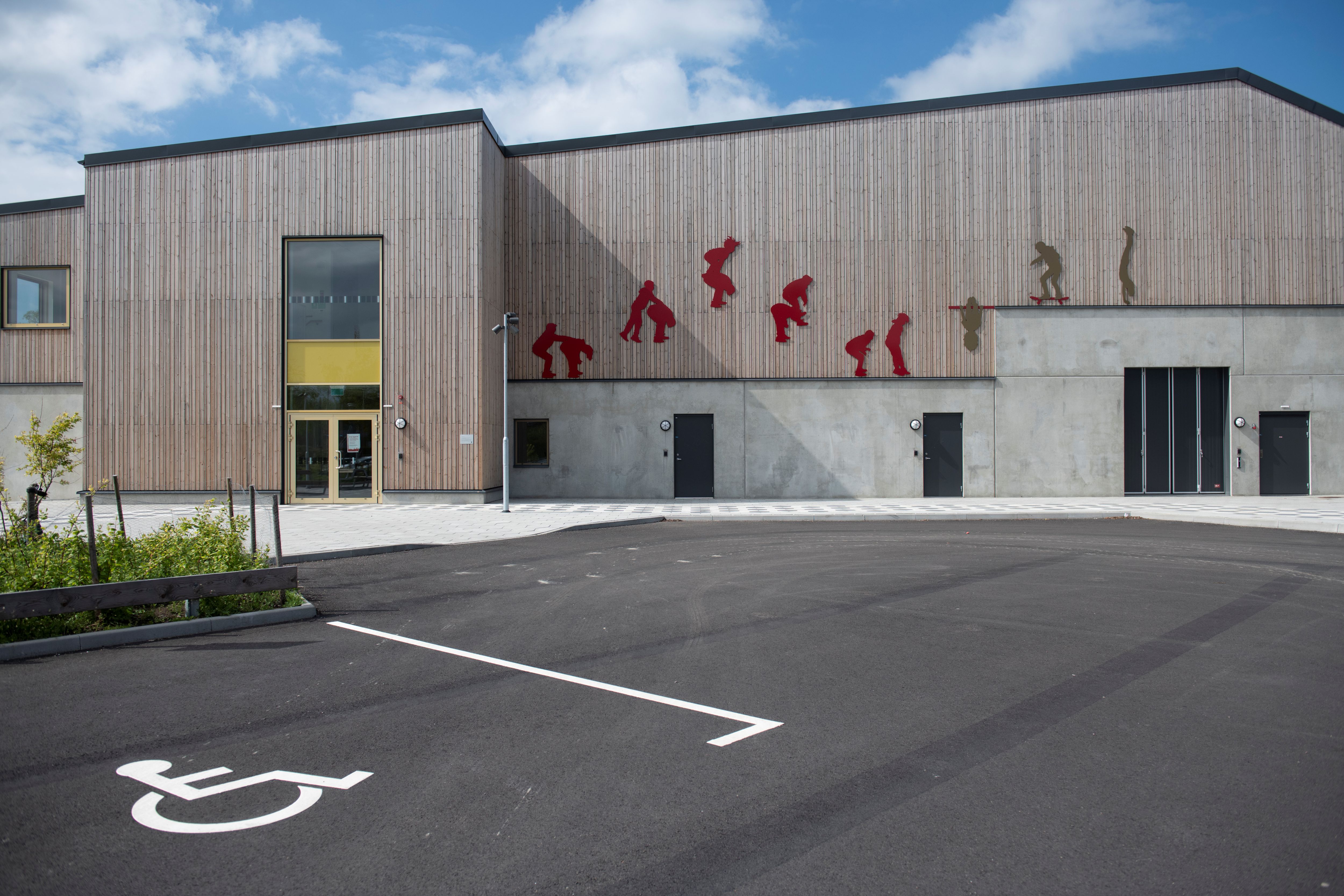 Idrottshall med siluetter av lekande barn på fasaden