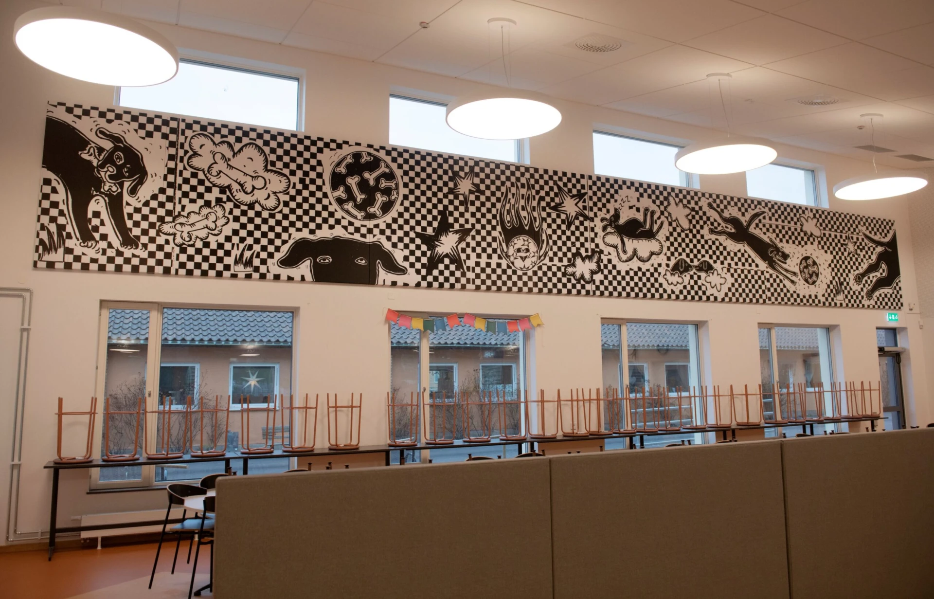 Matsal med bild på väggen som föreställer lekfulla hundar.