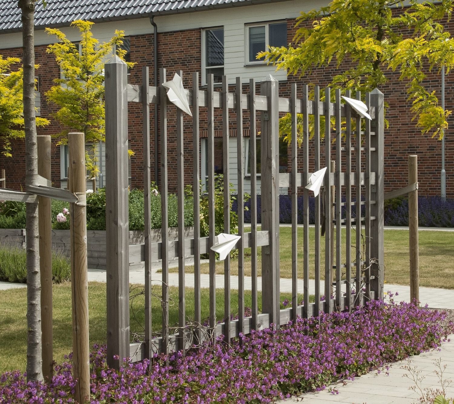 Konstverk: pappersflygplan på en spaljé.