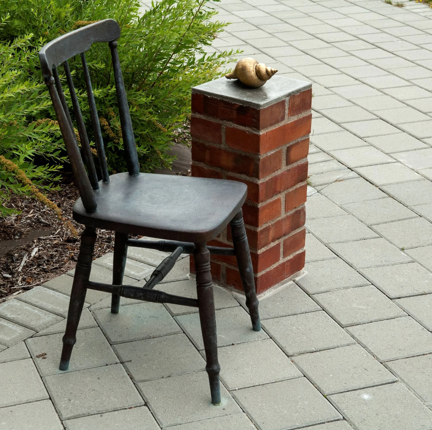 Skulptur av en gammal stol i brons och en förgylld snäcka.