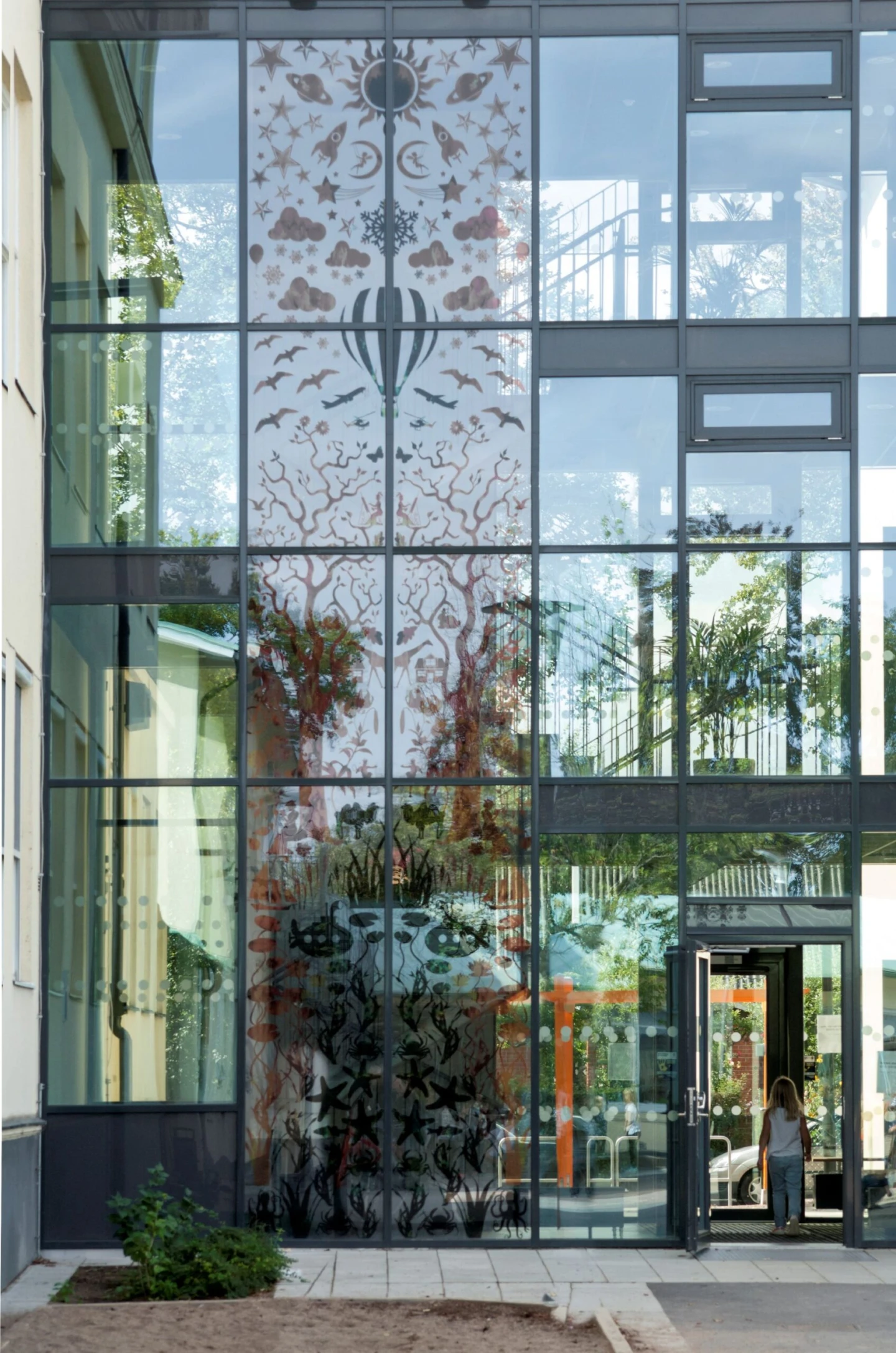 Konstverk i form av semi-transparenta siluetter på glasvägg.