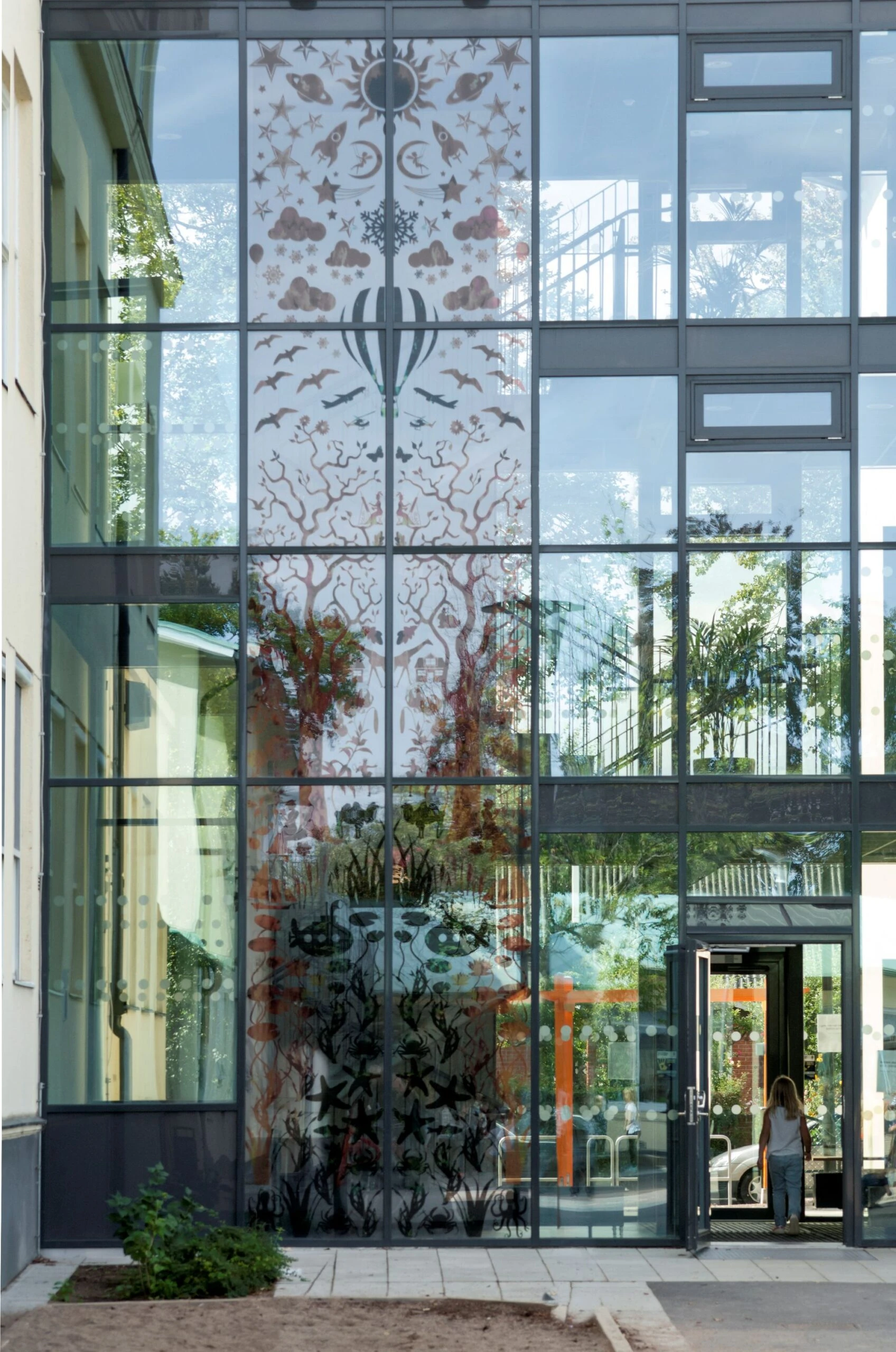 Konstverk i form av semi-transparenta siluetter på glasvägg.