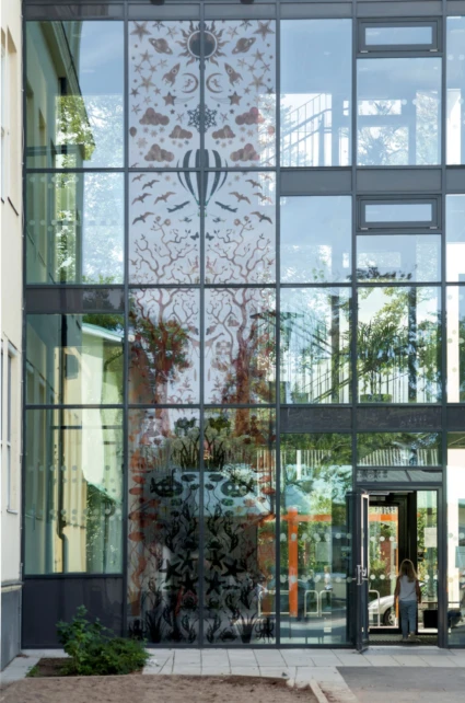 Konstverk i form av semi-transparenta siluetter på glasvägg.