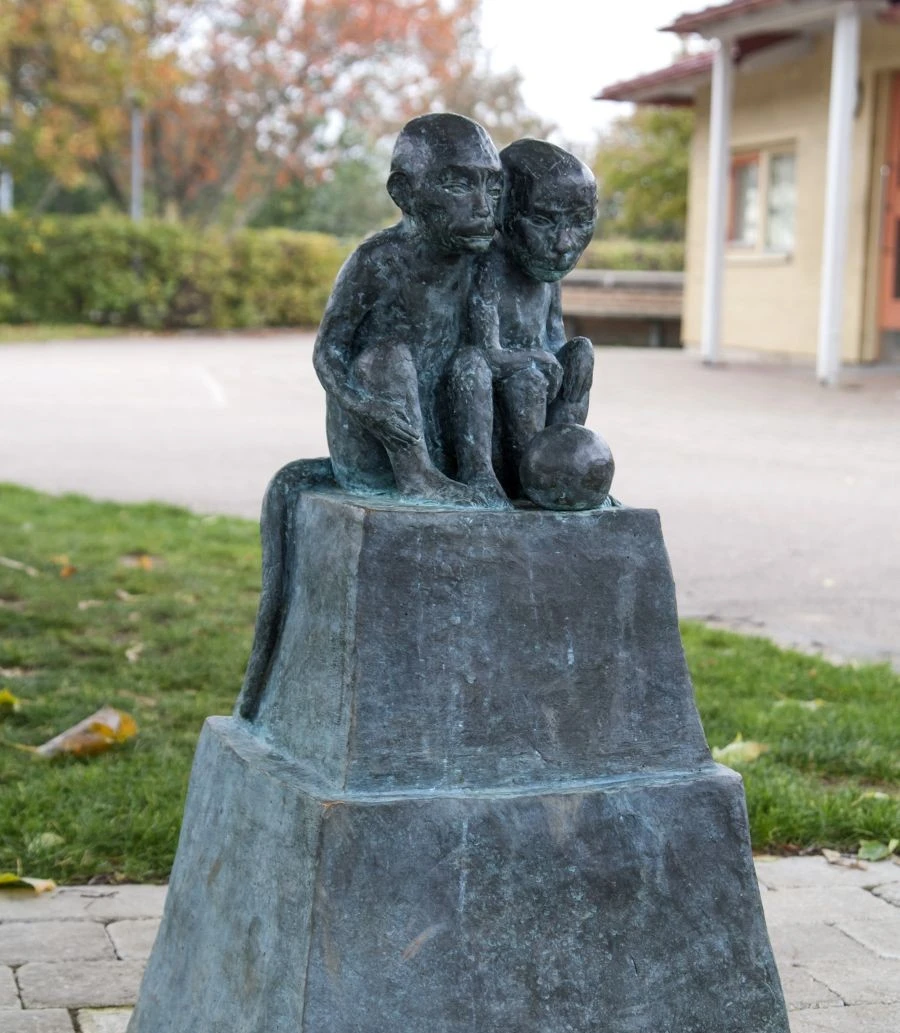 Skulptur av två små apor som sitter tätt tillsammans