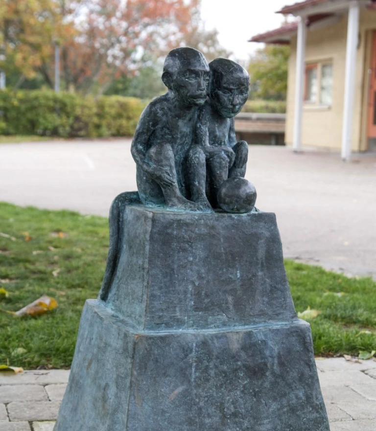 Skulptur av två små apor som sitter tätt tillsammans