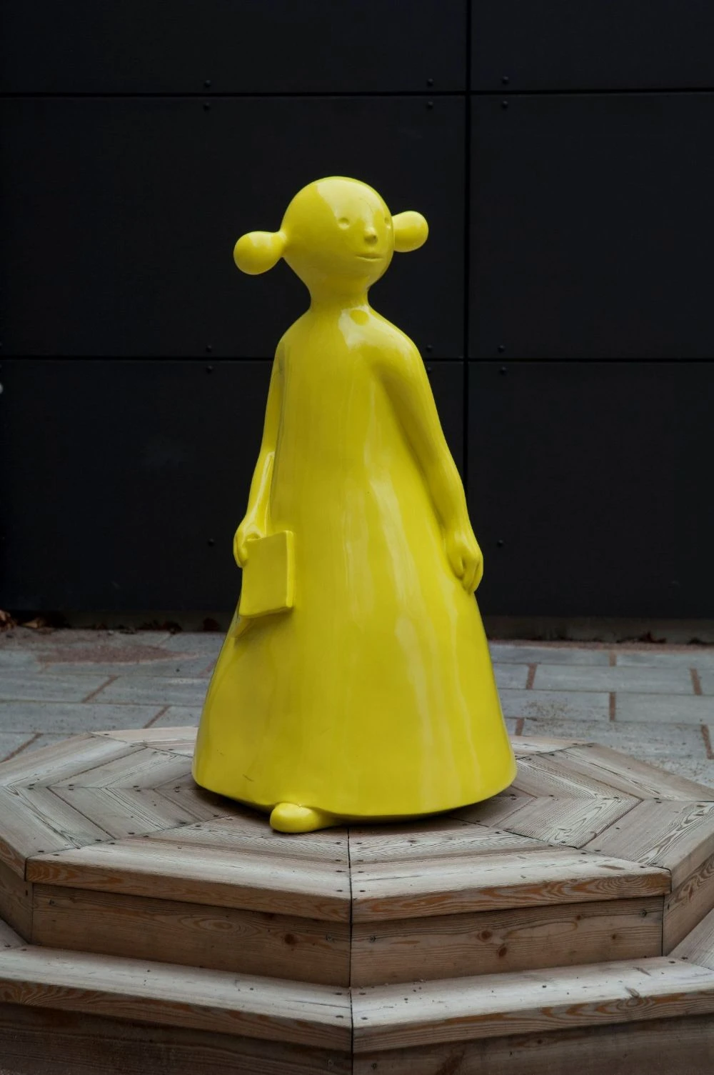 Gul skulptur av en figur med en bok i handen.