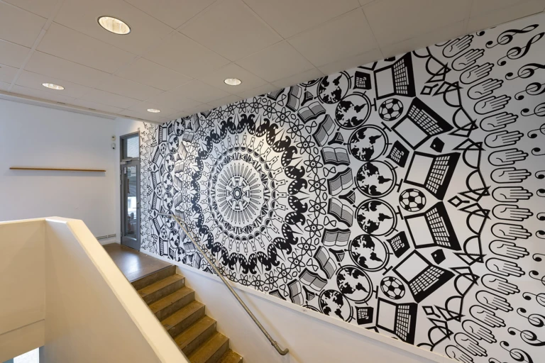 Konstverk i form av väggmålning i svart på vit vägg.