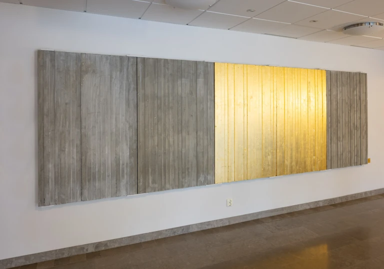 Konstverk i form av betongrelief med guldbelagt parti. Sitter i entrén.