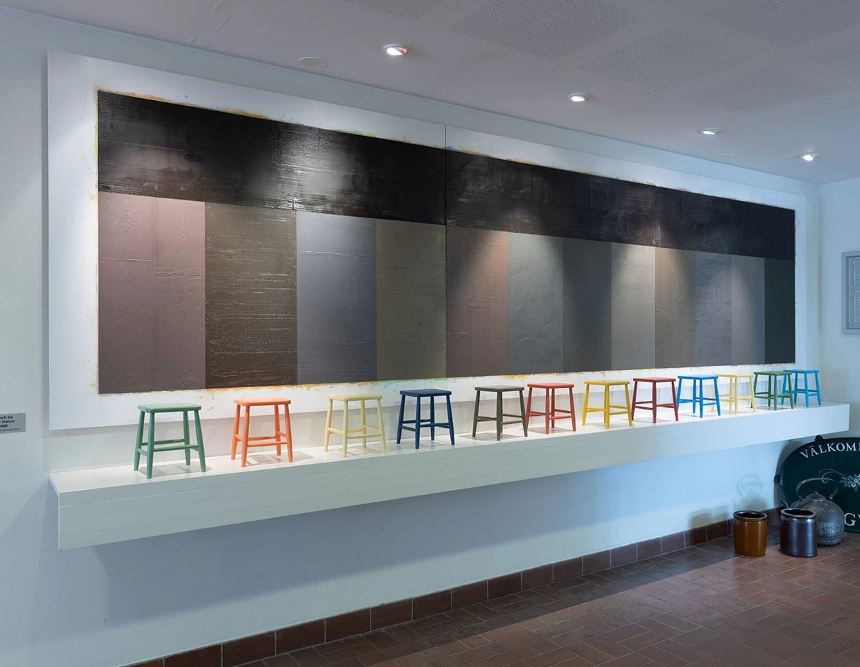 Konstverk med dova färgfält och små pallar på rad.