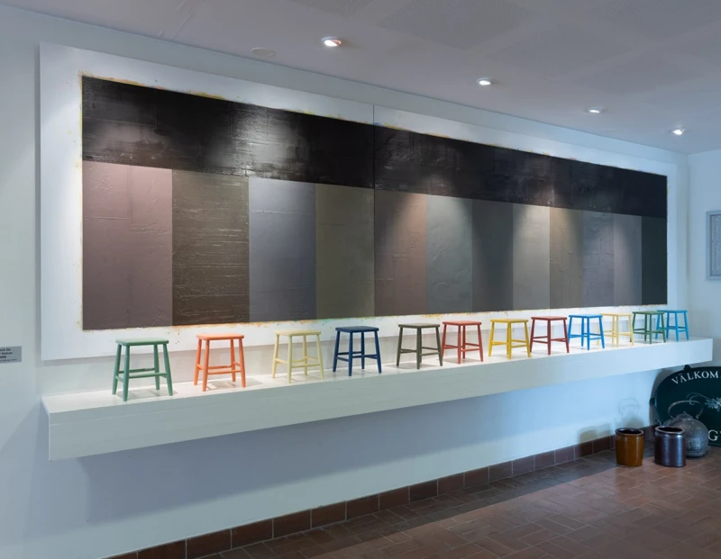 Konstverk med dova färgfält och små pallar på rad.