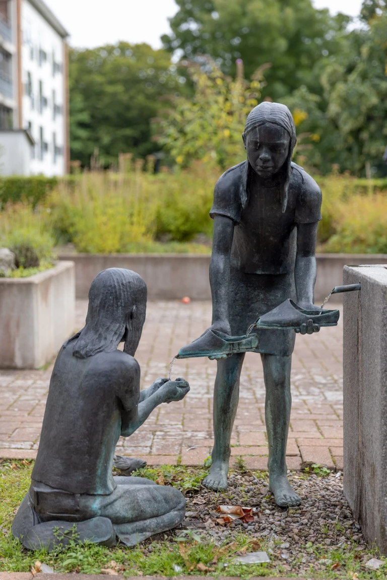 Vattenspel där två flickor gör en temporär vattenledning med hjälp av den ena flickans skor.