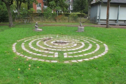 Konstverk på gräsmatta i form av två skulpturer och en labyrint.