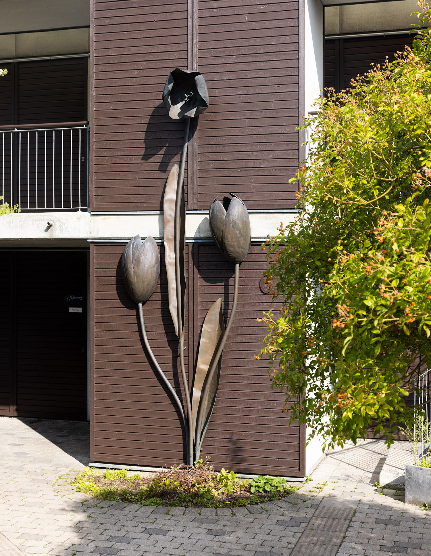 Konstverk i form av tulpan i metall på vägg.