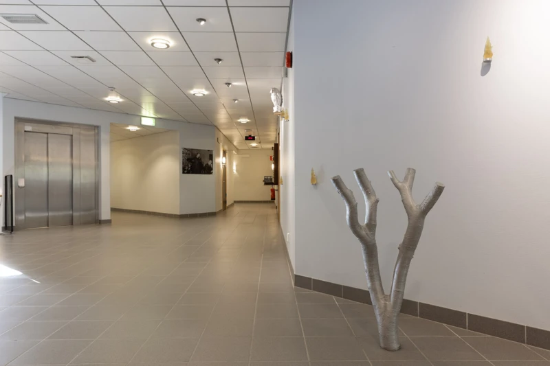 Rumslig gestaltning med skulpturer av uggla, trädgren och flammor. 