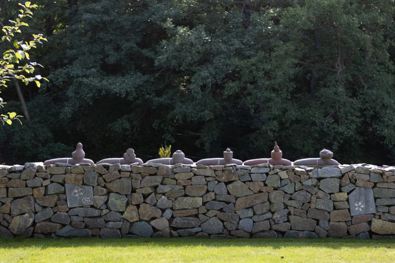 Konstverk i form av fantasifulla keramiksniglar på rad på en mur. 