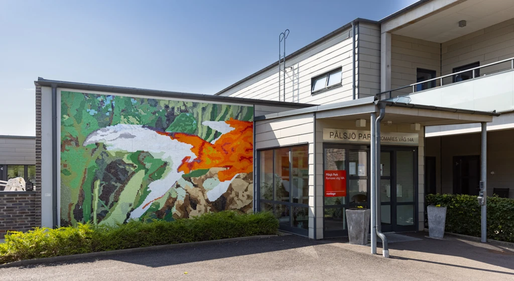 Konstverk på vägg inne och ute i forma av en mosaik av en guldfisk.