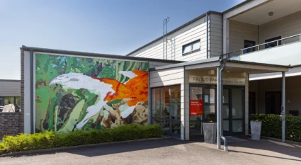 Konstverk på vägg inne och ute i forma av en mosaik av en guldfisk.