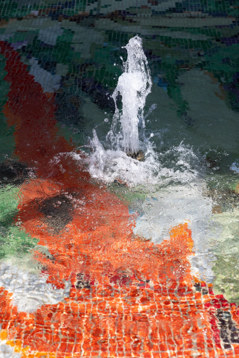 Konstverk i fontän med guldfiskmosaik i botten. 