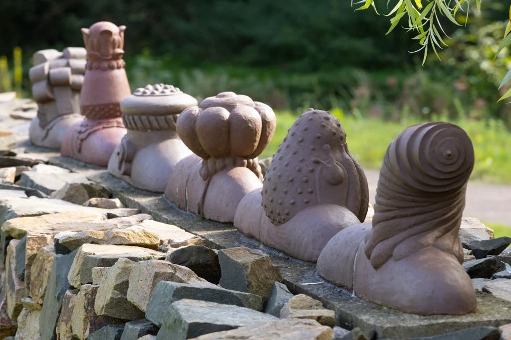 Konstverk i form av fantasifulla keramiksniglar på rad på en mur.