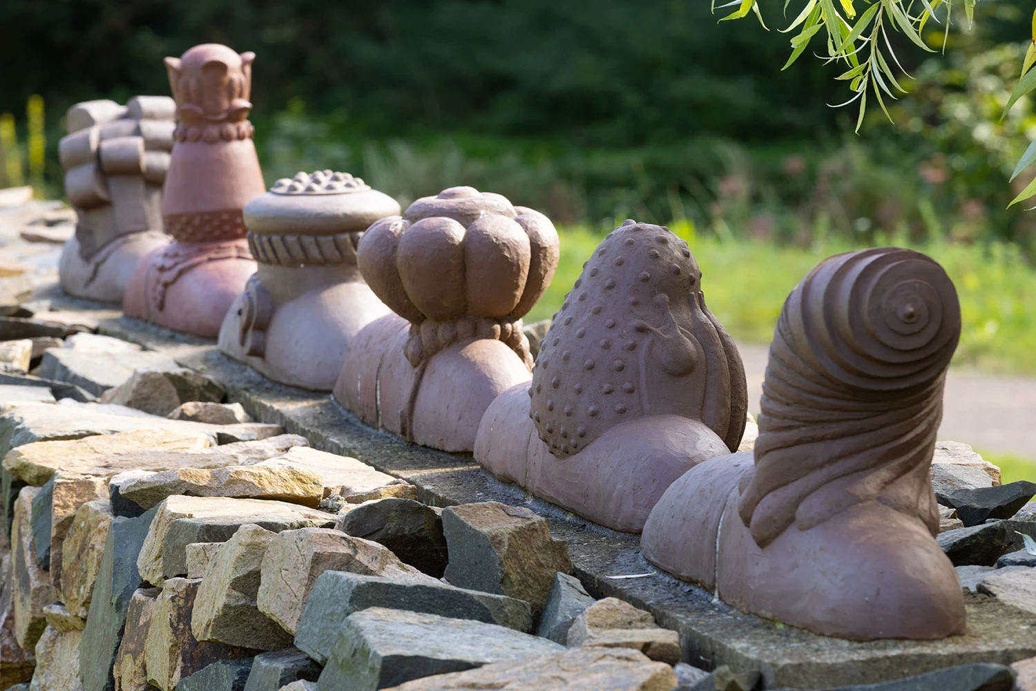 Konstverk i form av fantasifulla keramiksniglar på rad på en mur.