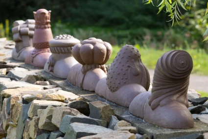 Konstverk i form av fantasifulla keramiksniglar på rad på en mur.