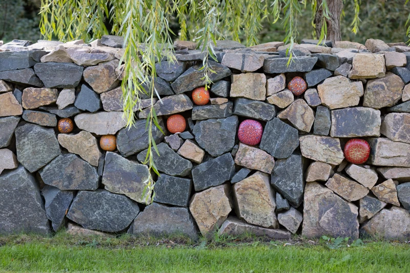 Konstverk i kallmur bestående av glasbollar i rött. 