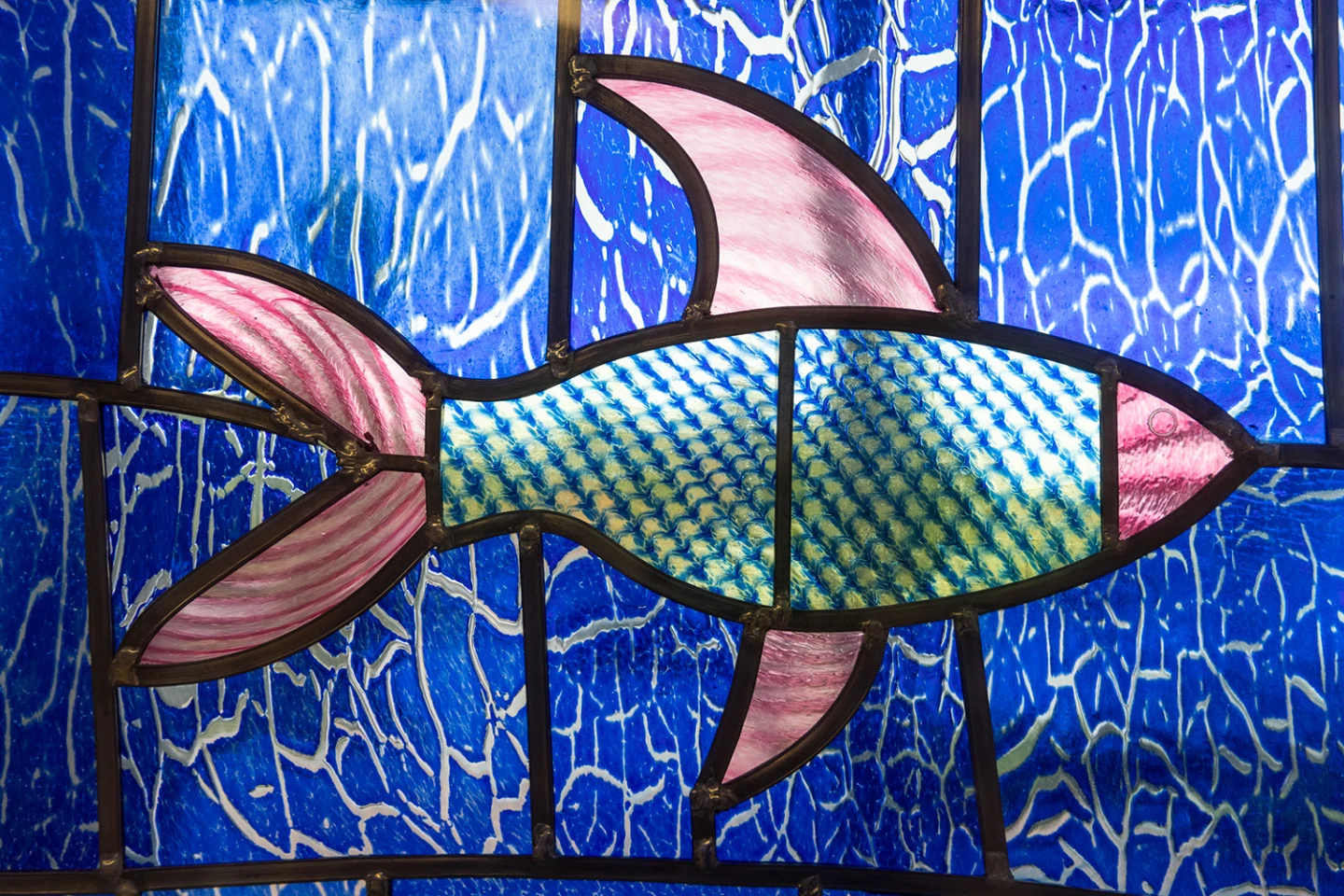 Detalj av blyinfattat glas med fisk som motiv. Glaskonstverk.