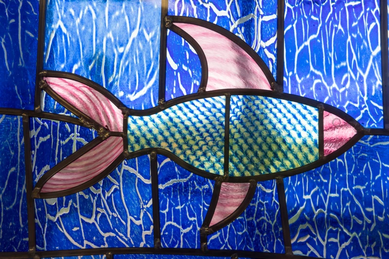 Detalj av blyinfattat glas med fisk som motiv. Glaskonstverk.