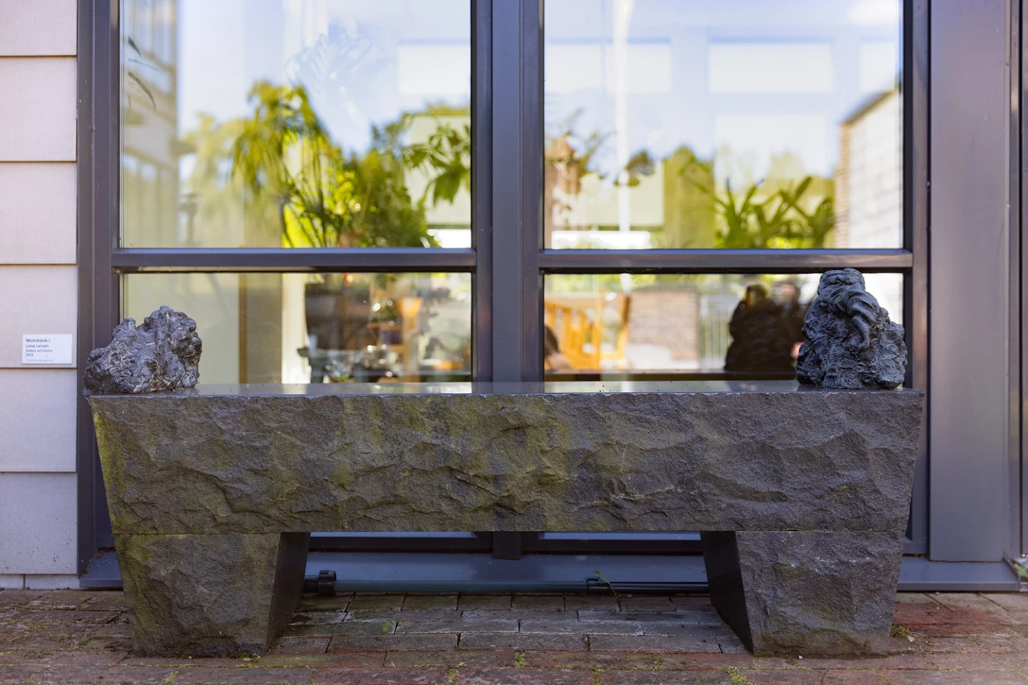 Konstverk i form av bänk i brons och sten.
