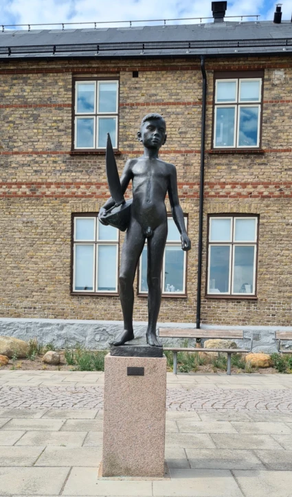 Skulptur av pojke med båt i handen.