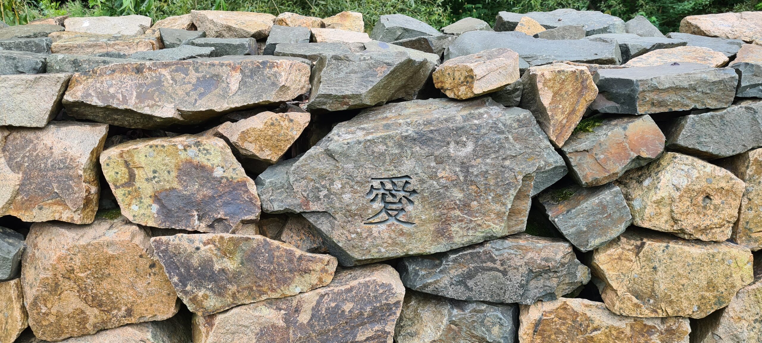 Sten i mur med inristat japanska tecken.