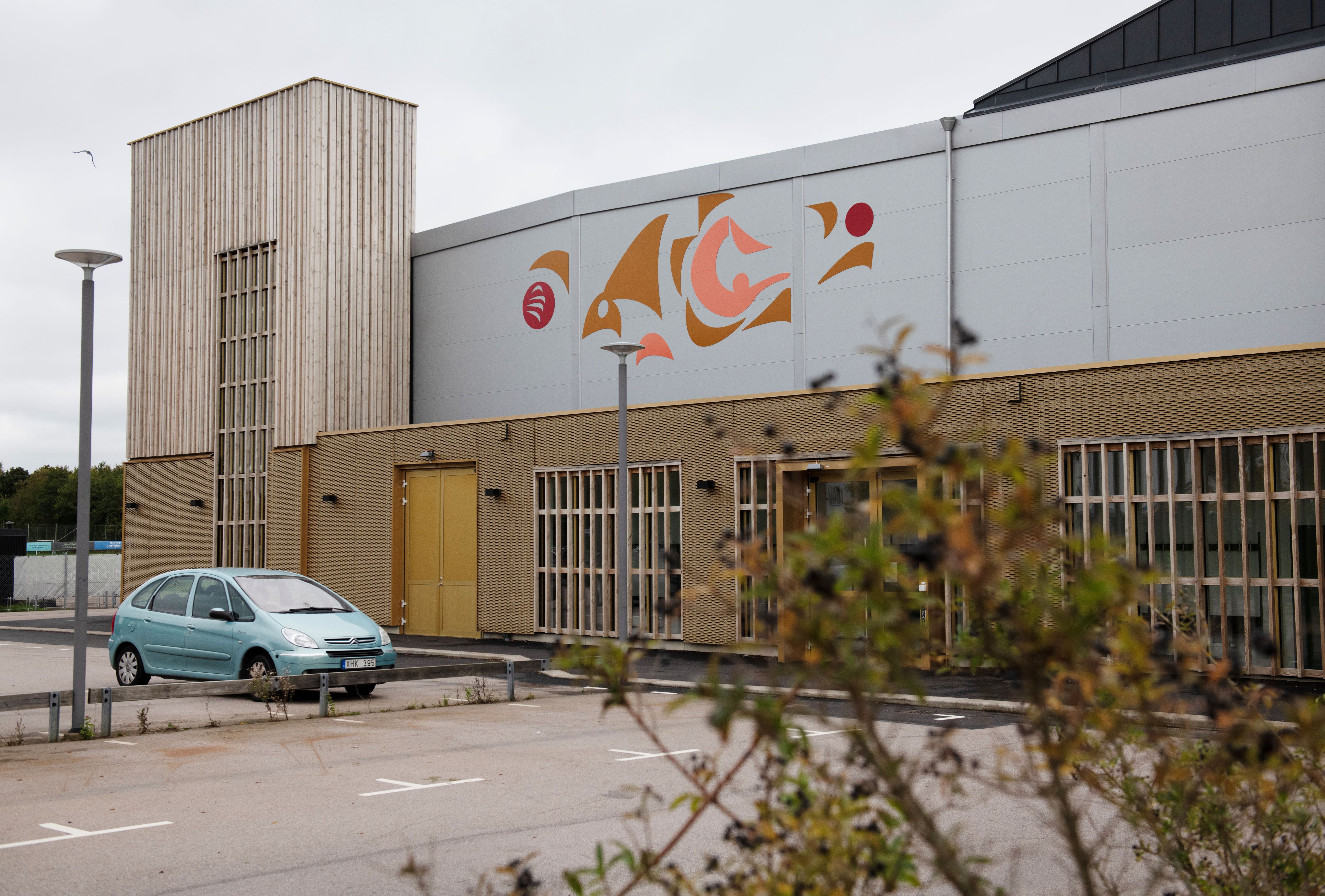 Bild av abstrakt konstverk i röda toner på fasad. 