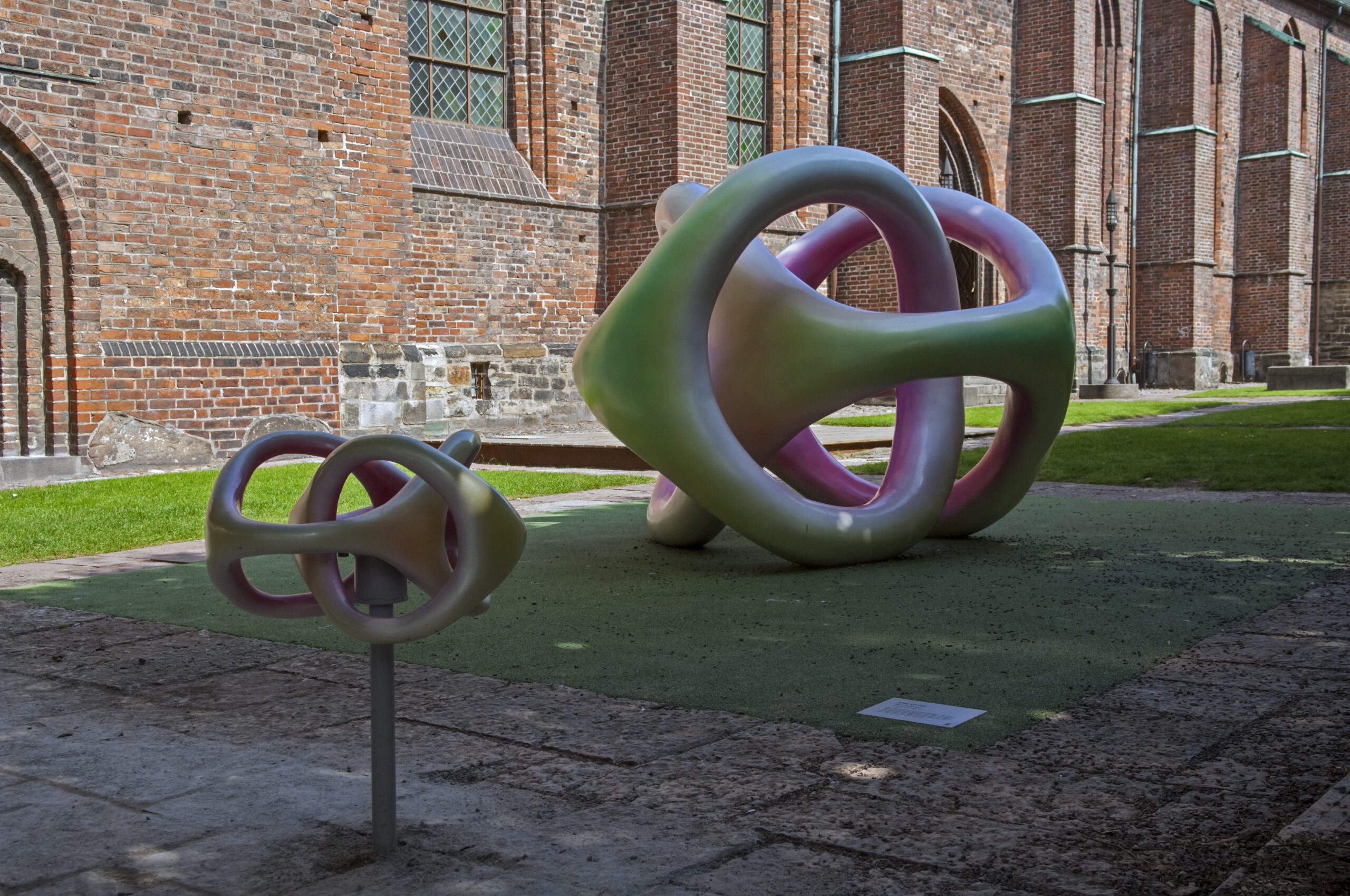 Två skulpturer i regnbågens färger med intrikata former.