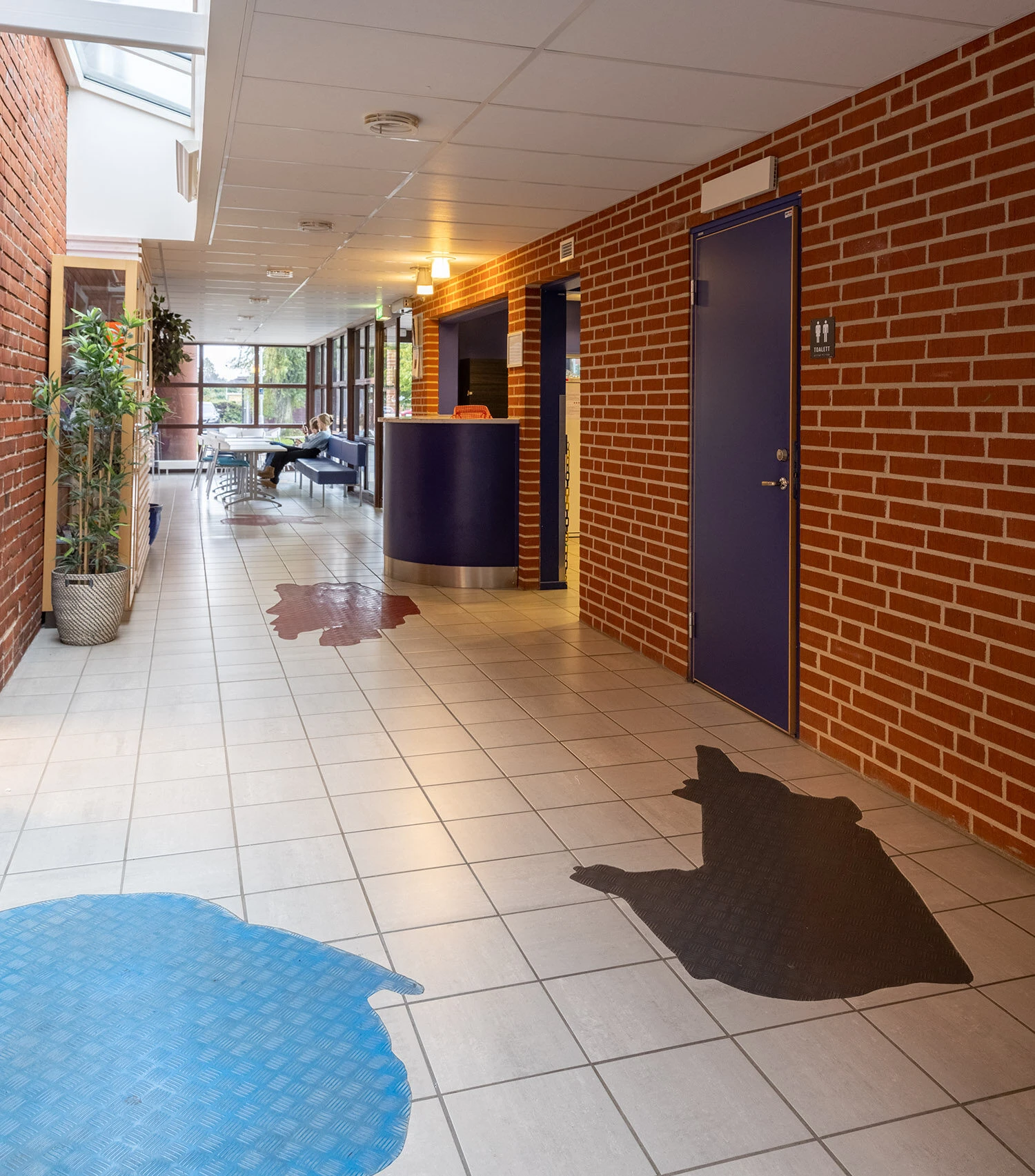 Konstverk på golvet i en korridor i form av olikfärgade former.